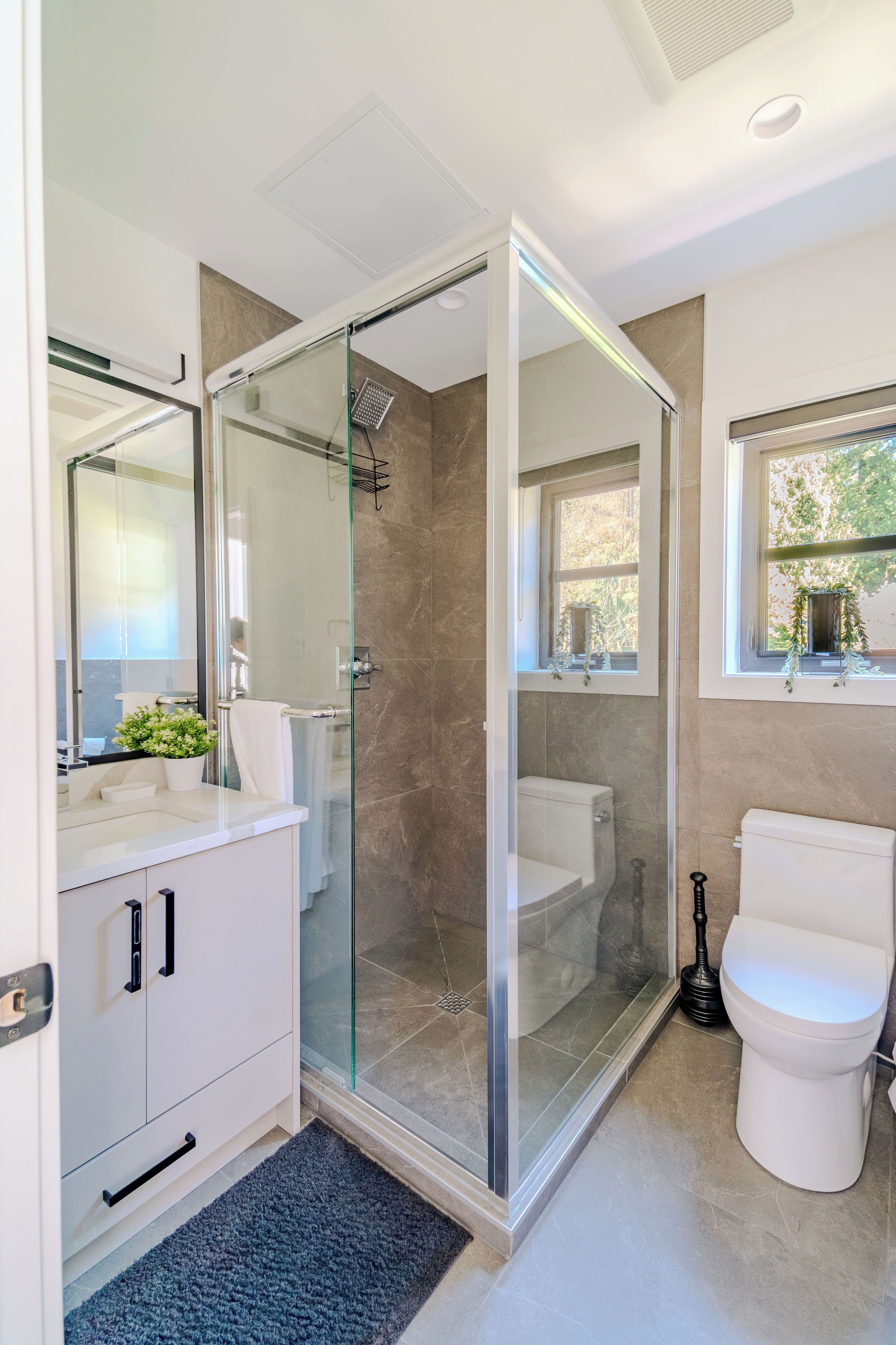 Un bagno moderno con doccia vetro, un WC bianco e un mobile lavabo con specchio.