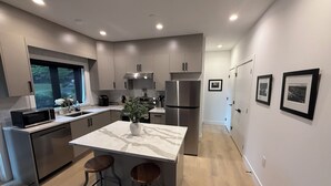 Een moderne keuken met een centraal eiland, roestvrijstalen apparatuur en uitzicht op het buiten.