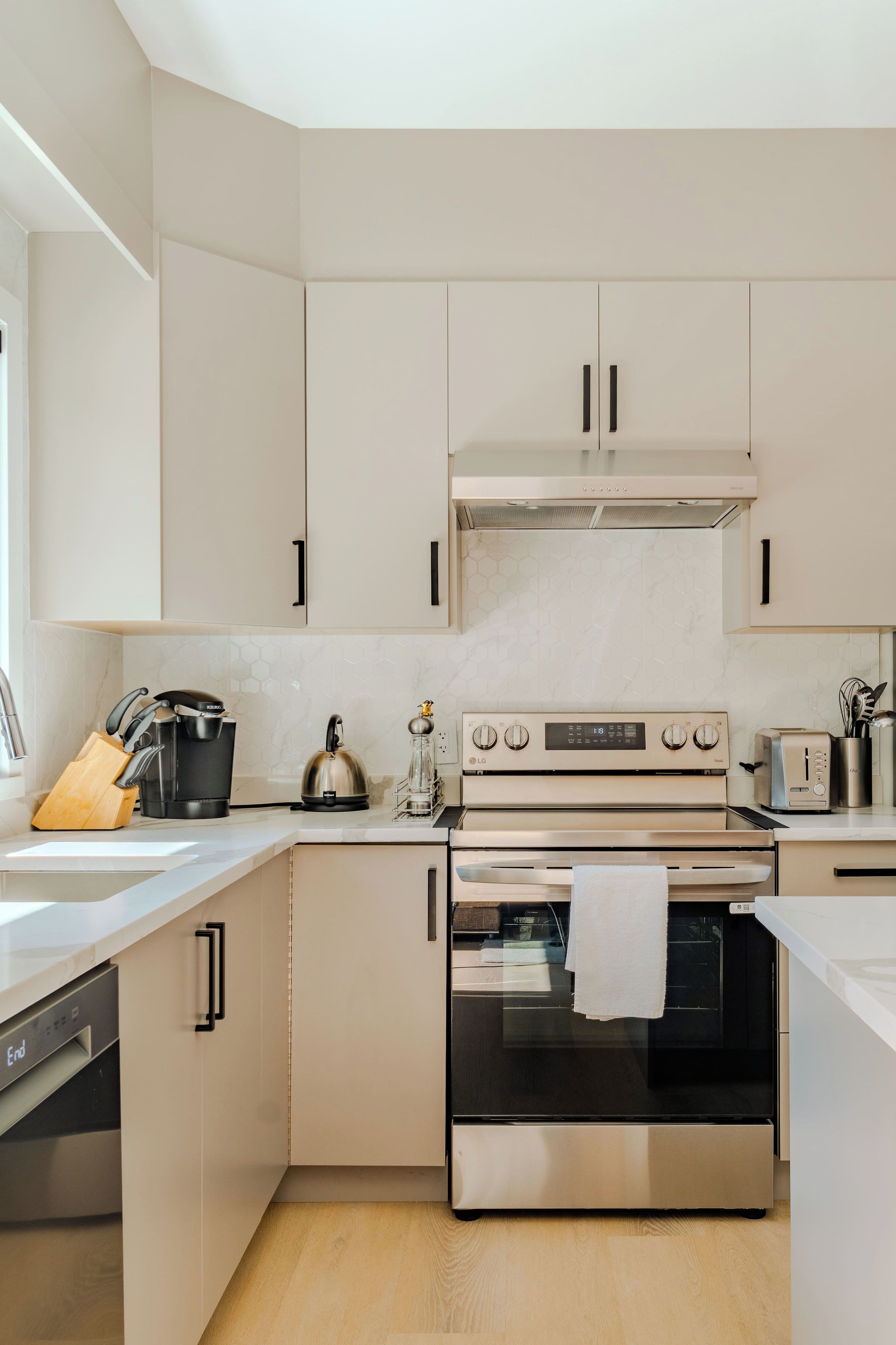 Une cuisine moderne avec des meubles blancs, des appareils en acier inoxydable et un plan de travail en bois.