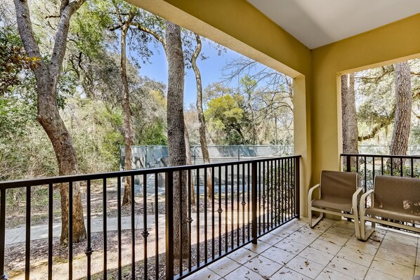 A balcony with a view of trees and a fence.