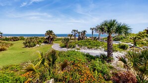 A golf course with a clear view of the ocean, surrounded by lush greenery and palm trees.