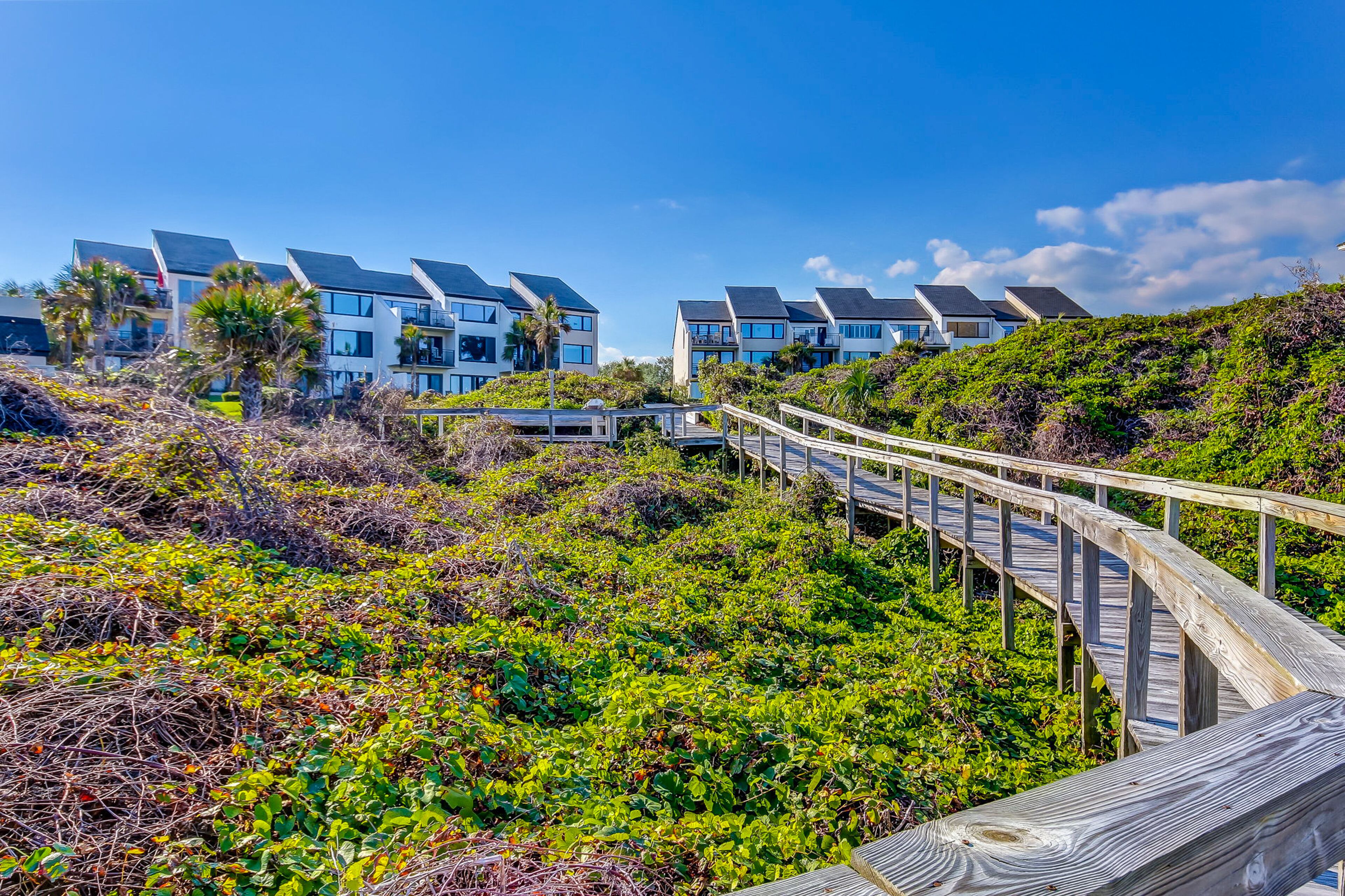 Un hôtel situé sur la côte, doté d’une architecture moderne, d’une promenade en bois et d’une végétation luxuriante.