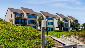 A modern multi-story residential building with balconies, large windows, and a landscaped garden area.