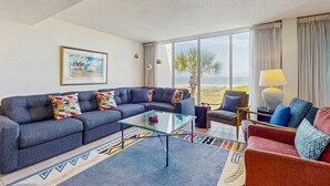 A modern living room with a sectional sofa, a glass coffee table, and a patterned rug.