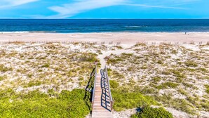 Una passerella in legno che conduce a una spiaggia con vista libera sull'oceano.