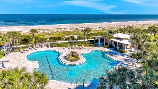 Un resort con una piscina grande, vista sulla spiaggia e palme.