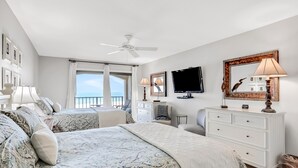 Una camera d'albergo con un letto, una scrivania, una televisione e un balcone con vista.
