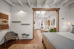 Un dormitorio acogedor con una cama, un banco y una mesita. Hay una puerta que da a otra habitación.