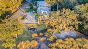 An aerial view of a two-story house with a large porch, surrounded by trees and a driveway.