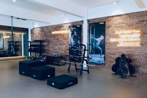 A gym with exercise equipment, a brick wall, and motivational posters. - JetPad Suites - Near KLIA (Dengkil)