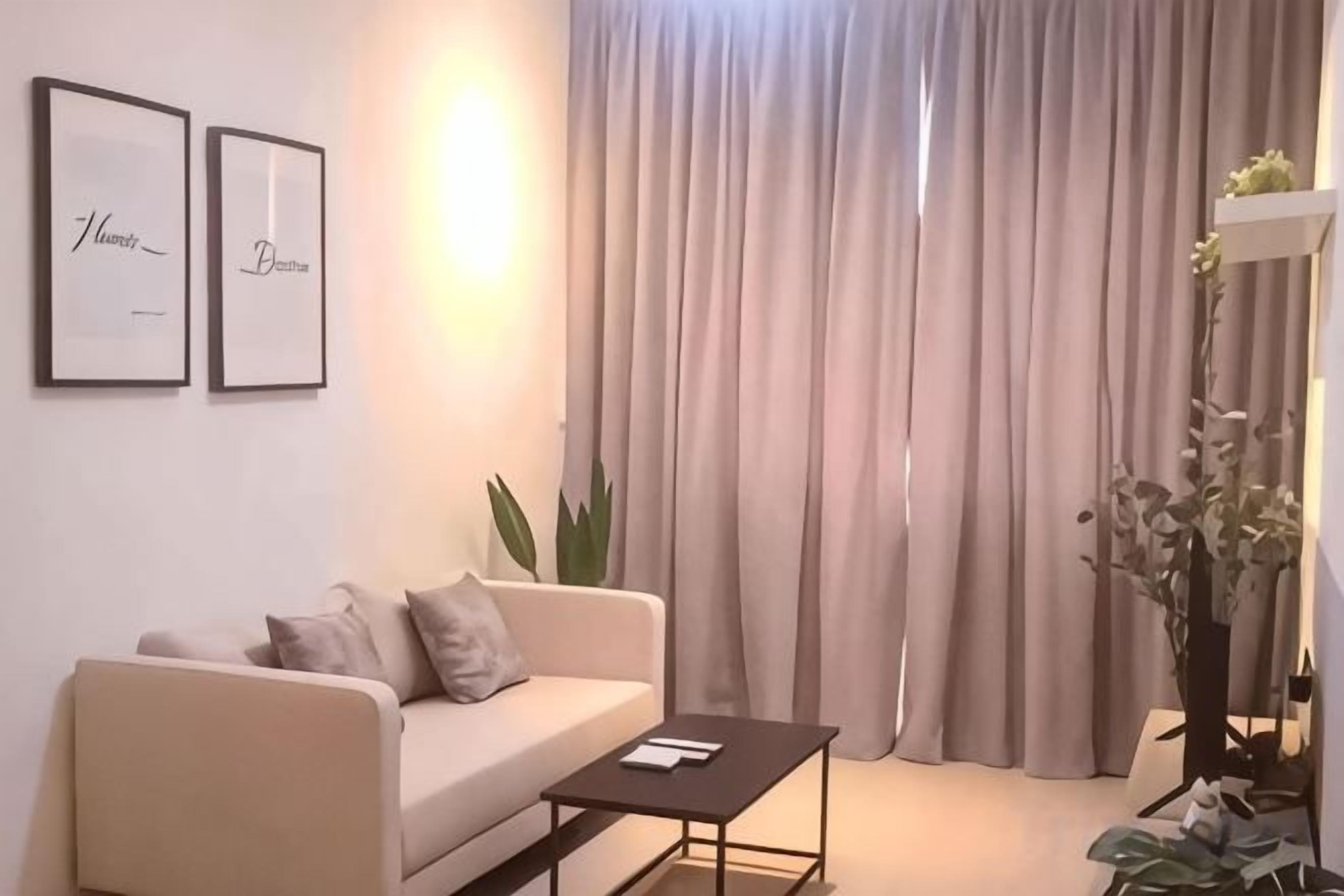 A modern living room with a sofa, a coffee table, and a large window with curtains.