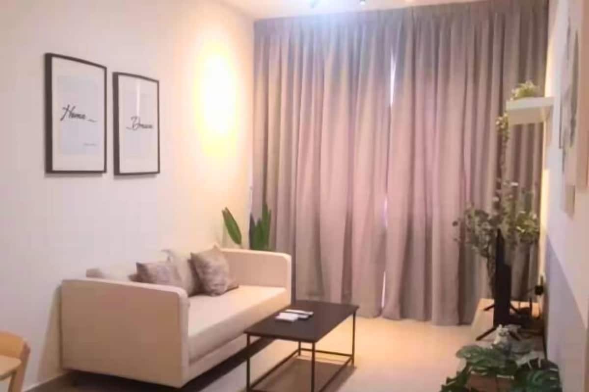 Un salon avec un canapé, une table basse et un téléviseur. Deux tableaux encadrés sont accrochés au mur.