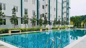 A swimming pool with a tiled edge, surrounded by a low white fence and small trees. - JetPad Suites - Near KLIA (Dengkil)