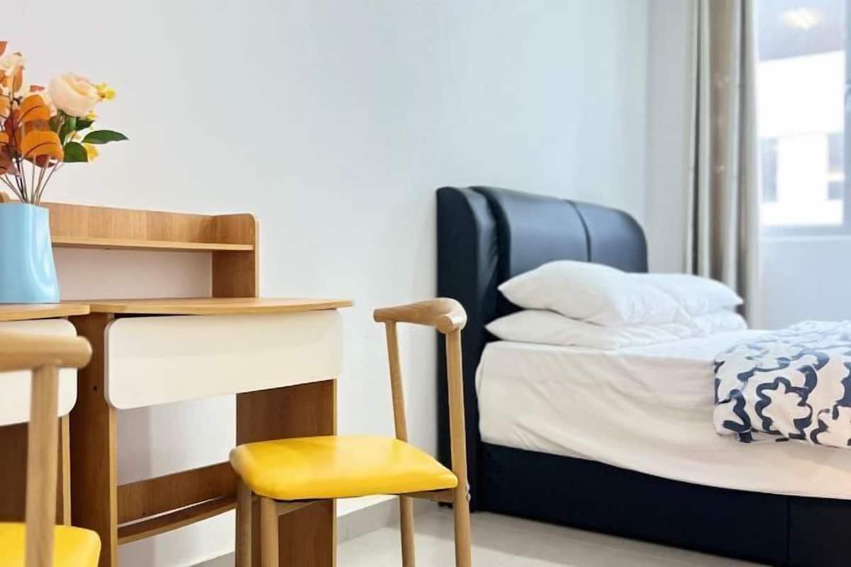 Une pièce comprenant un lit, un bureau, deux chaises et un vase de fleurs.