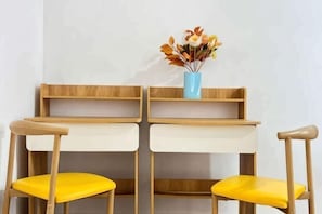 A table with two chairs, a vase with flowers, and a wooden shelf. - JetPad Suites - Near KLIA (Dengkil)