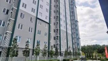 A multi-story residential building with balconies, a swimming pool, and a landscaped area with trees.