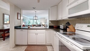A modern kitchen with white cabinetry, a black countertop, and a stainless steel range hood. - Updated, ground-floor condo in Amelia Island Plantation with patio & pool access (Fernandina Beach)