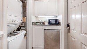 A compact kitchen with white cabinetry, a washing machine, a microwave, and a stainless steel refrigerator. - Dog-Friendly Tennis Villa Suite in Amelia Island w/Shared Pool, Free WiFi (Fernandina Beach)