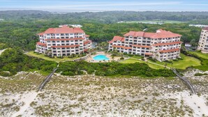 A multi-story hotel with a swimming pool, surrounded by lush greenery and a beach. - Beautiful Condo with Gorgeous Ocean Views from Balcony + Shared Pool & Free WiFi (Fernandina Beach)