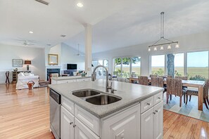 A spacious kitchen with a large island, a dining area with chairs, and a view of the outdoors.
