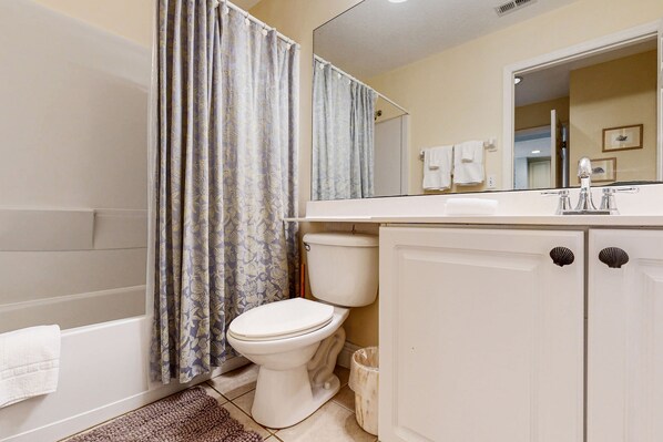 A bathroom with a bathtub, toilet, and vanity with a mirror.