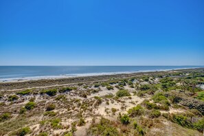 A coastal landscape with a beach, dunes, and sparse vegetation.