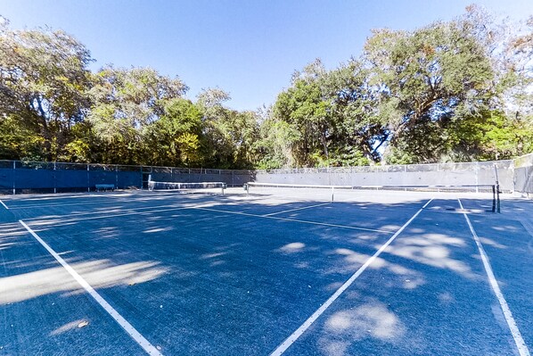 An outdoor tennis court with blue lines, surrounded by trees and a fence. - Dog-Friendly Home Located In Gated Community w/Shared Pool, WiFi, Central AC, WD (Fernandina Beach)