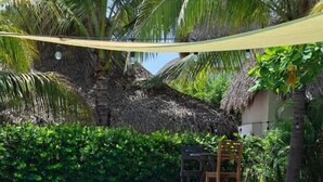 A swimming pool with clear blue water, surrounded by lush greenery and a thatched-roof structure. - Lemon Tree El Paredon (Sipacate)