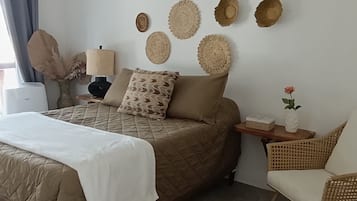 Un dormitorio con una cama, un tapete redondo, una mesita auxiliar y un ventilador de techo.