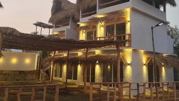 A two-story building with a thatched roof, wooden balconies, and a covered outdoor seating area. - Lemon Tree El Paredon (Sipacate)