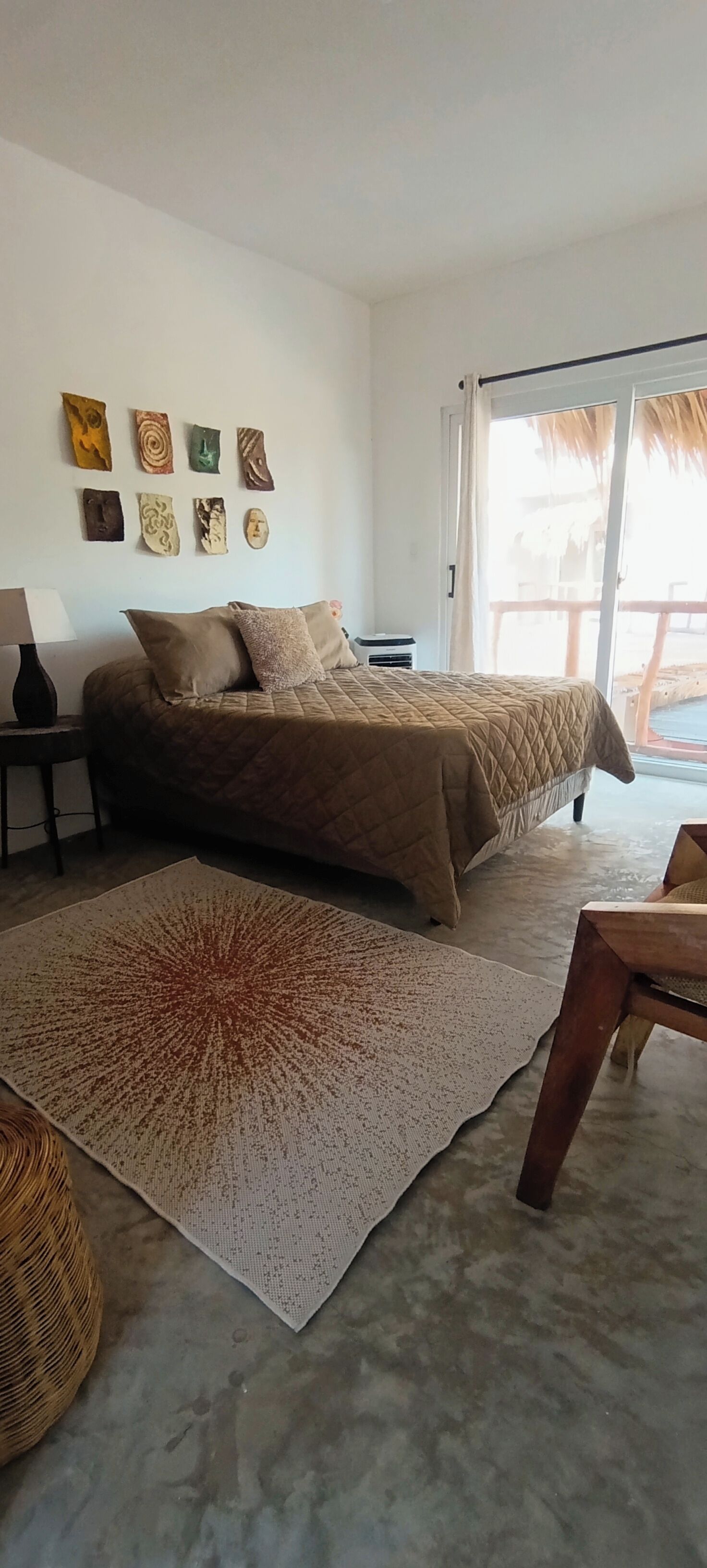 A bedroom with a bed, a large rug, a nightstand, and wall art.