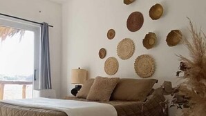 A bedroom with a bed, a ceiling fan, and a wall decorated with circular objects. - Lemon Tree El Paredon (Sipacate)