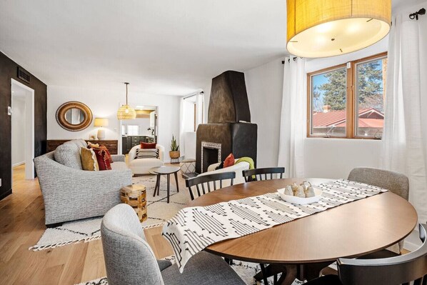 A modern living room with a fireplace, a dining table, and a view of the outside.