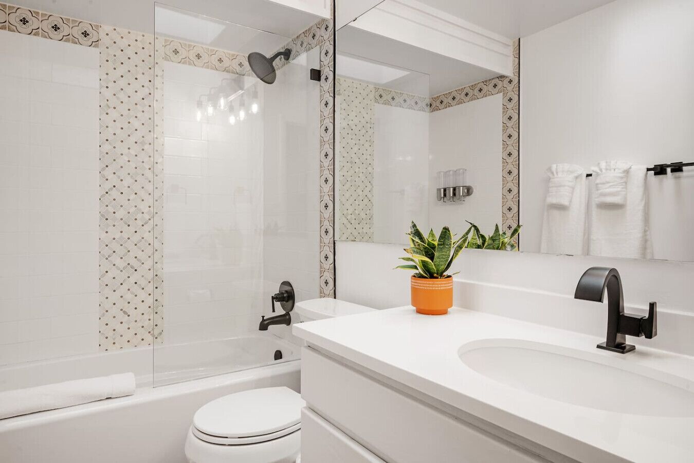 A modern bathroom with a white sink, black faucet, and a shower with a glass door.
