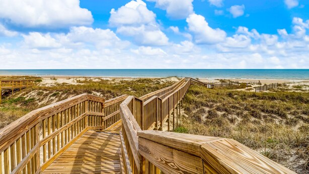 A wooden boardwalk leading to a beach with a clear sky and clouds. - Dog-friendly Beachwood home in Omni Plantation with pool & beach access (Fernandina Beach)