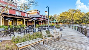 A wooden deck with outdoor seating and a building with a red facade. - Dog-friendly Beachwood home in Omni Plantation with pool & beach access (Fernandina Beach)