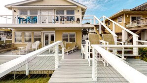 A two-story house with a deck, outdoor seating, and a staircase. - Spacious Beachfront Home w/Deck, Balcony, Central A/C, Washer/Dryer, and WiFi (Fernandina Beach)