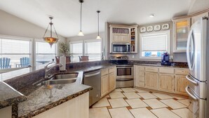 A modern kitchen with granite countertops, stainless steel appliances, and a large island. - Spacious Beachfront Home w/Deck, Balcony, Central A/C, Washer/Dryer, and WiFi (Fernandina Beach)