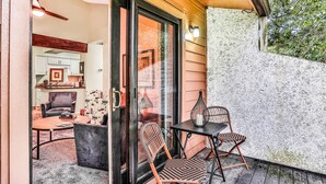 A covered patio with a table and chairs, a sliding glass door leading to an interior space with a ceiling fan, and a textured wall. - Quiet coastal escape within walking distance to beach with shared pool (Fernandina Beach)