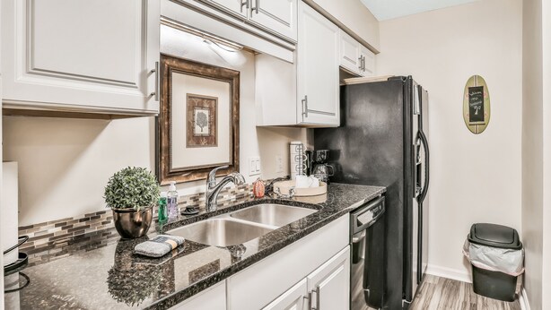 A kitchen with white cabinets, a black refrigerator, a sink, and a trash can. - Quiet coastal escape within walking distance to beach with shared pool (Fernandina Beach)