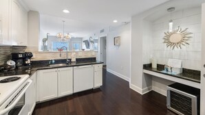 A modern kitchen with white cabinetry, a granite countertop, and a built-in oven.