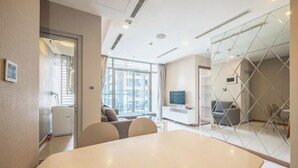 Une chambre d’hôtel moderne avec un grand lit, un bureau et une télévision. Elle dispose d’un balcon avec vue sur la ville.