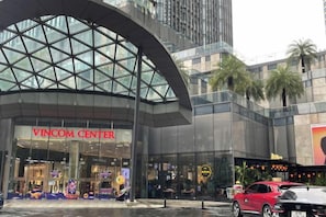 A modern building with a large glass entrance labeled 'VINCOM CENTER.' - Elysian Landmark Garden (Ho Chi Minh City)