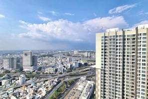 A high-rise building with multiple floors, a dense urban cityscape in the background, and a clear sky. - Elysian Landmark Garden (Ho Chi Minh City)