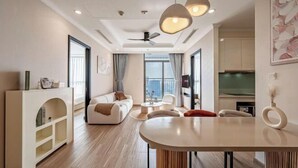 Un salon moderne avec un canapé, une table basse et un coin repas. On y trouve un ventilateur de plafond et des luminaires suspendus.
