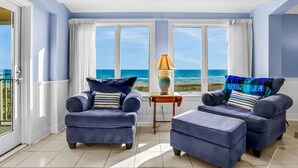 A room with two blue armchairs, a small table with a lamp, and a view of the ocean. - Oceanfront condo with balcony, AC, views & outdoor pool - dog-friendly (Fernandina Beach)