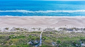 An aerial view of a beach with a pathway leading to a structure. - Oceanfront condo with balcony, AC, views & outdoor pool - dog-friendly (Fernandina Beach)