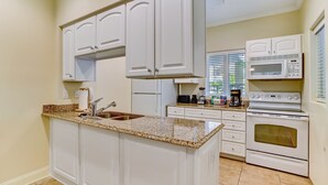 A kitchen with white cabinets, a granite countertop, a built-in oven, and a microwave. - Dog-Friendly Home in the Tennis Villas w/Free WiFi, Shared Pool, Central AC (Fernandina Beach)