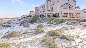 Un bien immobilier situé en bord de mer, composé de plusieurs bâtiments à étages, de balcons et d’espaces de détente en plein air.