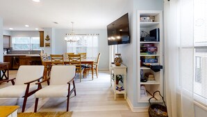 Un salon moderne comprenant un coin repas, une cuisine et un téléviseur fixé au mur.